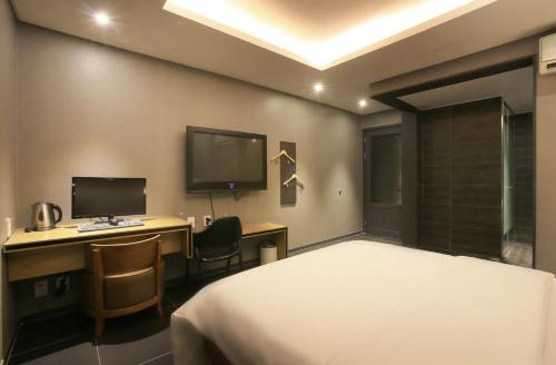 a bedroom with a bed and a desk with a computer at Zenith Hotel Bupyeong in Incheon