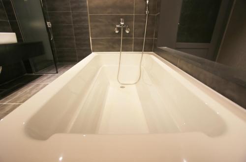 a large white bath tub in a bathroom at Zenith Hotel Bupyeong in Incheon