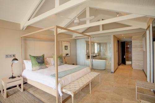 1 dormitorio con cama con dosel y baño en Abalone Guest Lodge, en Hermanus