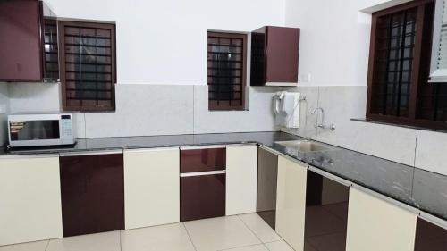a kitchen with a sink and a microwave at Mahika homestay, Peroorkada, Thiruvananthapuram in Trivandrum