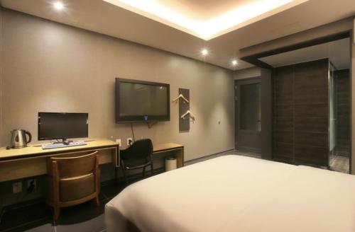 a bedroom with a bed and a desk with a computer at Zenith Hotel Bupyeong in Incheon