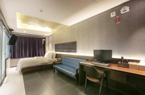 a hotel room with a couch and a desk with a computer at Zenith Hotel Bupyeong in Incheon