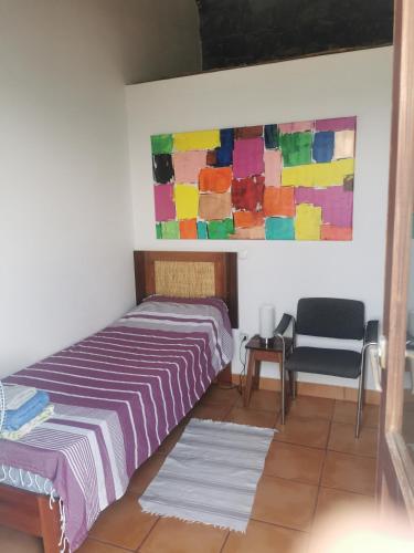 a bedroom with a bed and a painting on the wall at Casa Praia Tarrafal de Monte Trigo in Seladinha