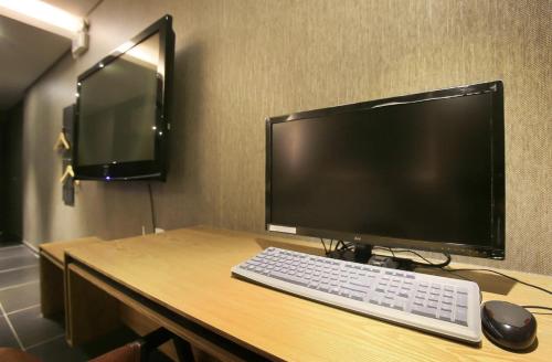 a computer monitor and a keyboard and mouse on a desk at Zenith Hotel Bupyeong in Incheon
