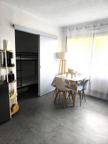 un salon avec une table et des chaises et une chambre dans l'établissement La Désirade avec Parking- Port - WIFI couchage en 160 neuf, au Cap d'Agde