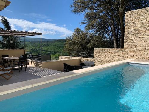 une piscine avec une table et des chaises à côté d'un bâtiment dans l'établissement La Calade de Goult, à Goult