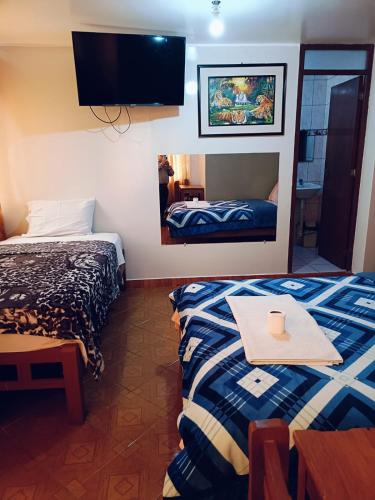 a room with two beds and a table and a mirror at Hospedaje Escorpio in Lima