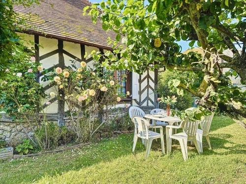 une table et des chaises sous un arbre dans une cour dans l'établissement La pomme bleu, à Deauville