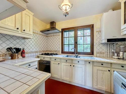 une cuisine avec des armoires blanches, un évier et une fenêtre dans l'établissement La pomme bleu, à Deauville