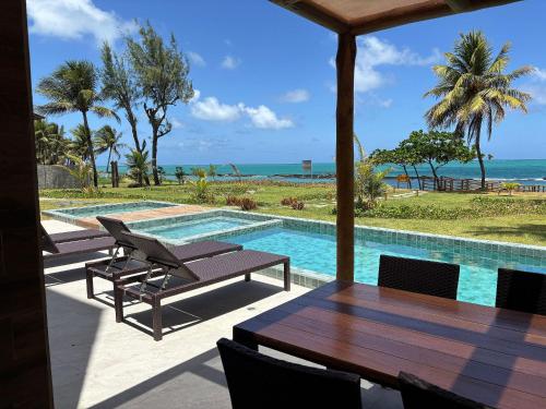 a swimming pool with a table and chairs and the ocean at Kauai Beach Residence in Tamandaré