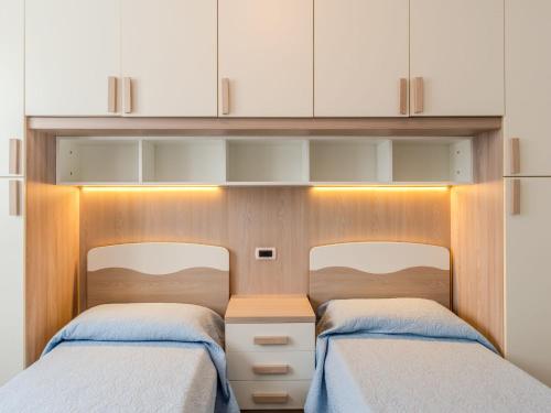 two beds in a small room with white cabinets at Apartment Il Melo-2 by Interhome in Garzeno