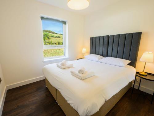 a bedroom with a large white bed with two towels on it at Apartment Craigmonie Apartment by Interhome in Drumnadrochit