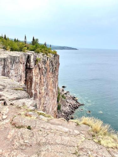 a cliff next to the ocean with trees on it at Ski in Ski out Cozy Studio Condo, Pool, Hot Tub, Views of Moose Mtn in Lutsen