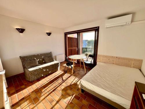 une chambre avec un lit, un canapé et une table dans l'établissement Studio calme avec piscine, parking privé, et accès proche à la mer - 4 couchages - FR-1-226A-125, à Fréjus