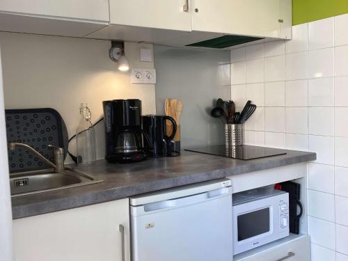une cuisine avec un évier et un micro-ondes dans l'établissement Studio confortable face aux Thermes avec balcon - FR-1-553-26, à Balaruc-les-Bains