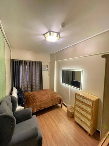 a bedroom with a bed and a couch and a television at Two Bedroom with Balcony 70sqm -Pasig in Manila