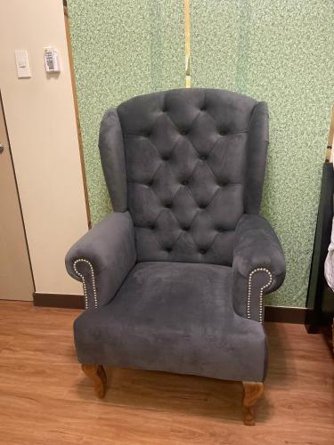 a gray chair in a room with a green wall at Two Bedroom with Balcony 70sqm -Pasig in Manila