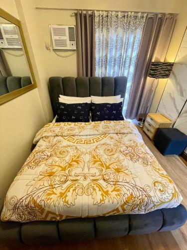 a bedroom with a bed with a gold and white comforter at Two Bedroom with Balcony 70sqm -Pasig in Manila