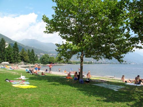 a group of people sitting on the grass near a lake at Apartment Il Melo-1 by Interhome in Garzeno