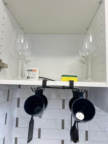 - une cuisine avec des verres à vin et des ustensiles sur une étagère dans l'établissement Comfortable studio Notre-Dame de Lorette Rodier, à Paris