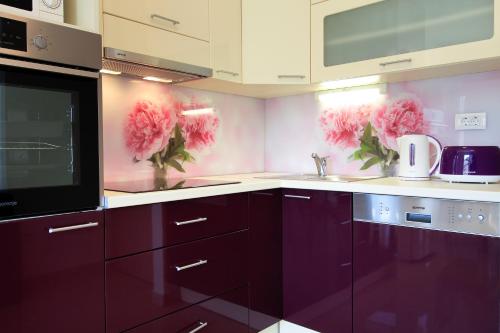 a kitchen with purple cabinets and pink flowers on the wall at Apartmani Podest II in Baška Voda