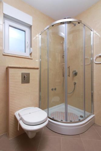 a bathroom with a shower with a toilet and a window at Apartmani Podest II in Baška Voda