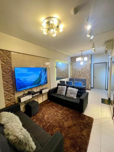 a living room with a couch and a large screen tv at Two Bedroom with Balcony 70sqm -Pasig in Manila