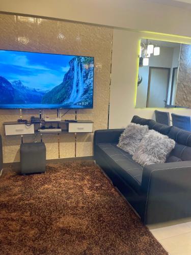 a living room with a blue couch and a large tv at Two Bedroom with Balcony 70sqm -Pasig in Manila