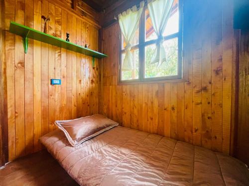 a bed in a wooden room with a window at Finca Maracuba Cabañas Limón, Manzana y Níspero in Jardin