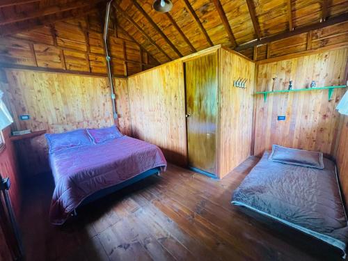 a bedroom with two beds in a wooden house at Finca Maracuba Cabañas Limón, Manzana y Níspero in Jardin