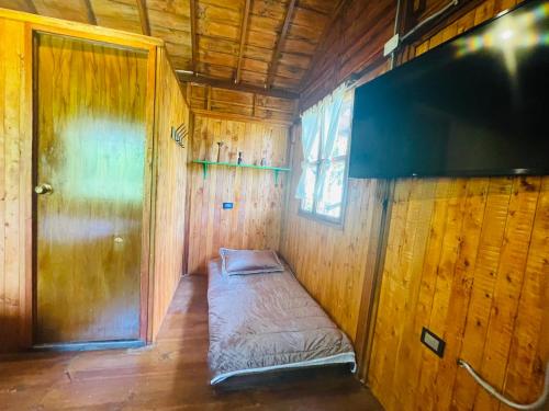a small room with a bed in a wooden wall at Finca Maracuba Cabañas Limón, Manzana y Níspero in Jardin