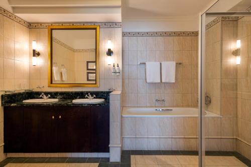 a bathroom with two sinks and a tub and a mirror at Mövenpick Hotel Windhoek in Windhoek