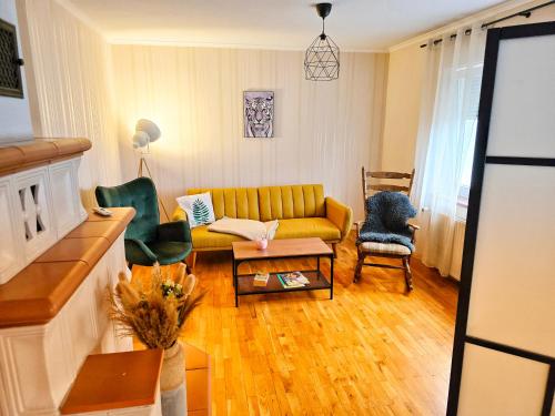 a living room with a yellow couch and chairs at Ferienwohnungen Lindenhof in Falkenberg