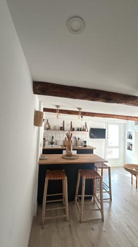 - une cuisine avec une table et deux tabourets dans une pièce dans l'établissement Place aux huiles, à Marseille