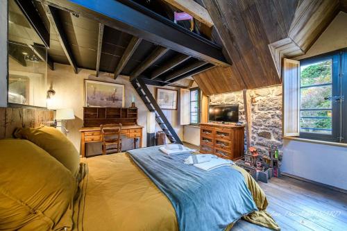 - une chambre avec un grand lit dans une pièce dotée d'un mur en pierre dans l'établissement Demeure A Fleur de Rance -5 étoiles- Saint-Malo, à Saint-Malo