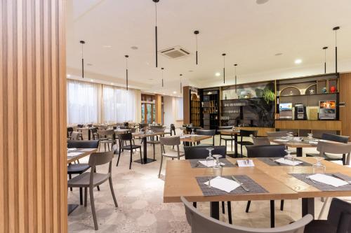 Hotel Villaggio Roller Club في كابو فاتيكانو: غرفة طعام مع طاولات وكراسي خشبية