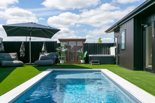 a backyard with a swimming pool and an umbrella at Heated Pool Gym Sauna Hot Tub in Taupo