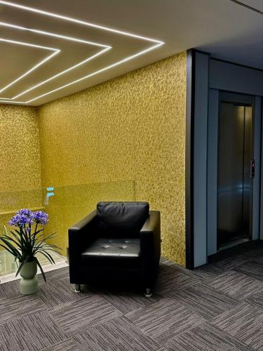 a black leather chair in a room with a yellow wall at Ador Hotel North Mitrovica in Mitrovicë