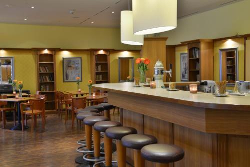 a bar in a restaurant with a row of stools at PLAZA INN Leonberg in Leonberg