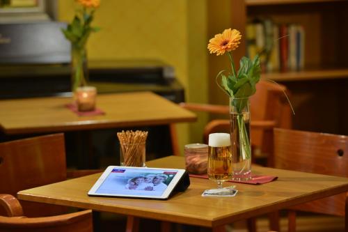 a wooden table with a laptop and a vase with flowers at PLAZA INN Leonberg in Leonberg