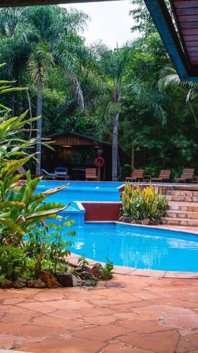 a blue swimming pool with palm trees in the background at La Aldea De La Selva Lodge in Puerto Iguazú