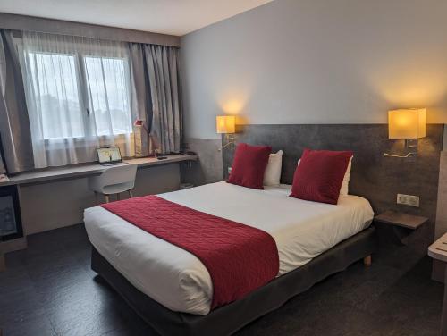 a hotel room with a large bed with red pillows at Hotel L'Hotan in Portet-sur-Garonne