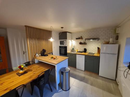 a kitchen with a wooden table and a kitchen with a refrigerator at Gîte Le Petit Velours in Lancié