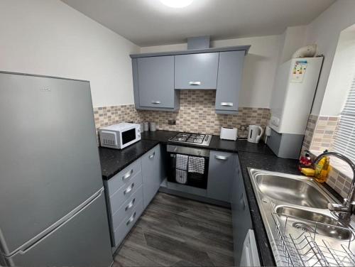 a small kitchen with a sink and a microwave at The Modern Balcony Apartment - 2 Bed 1 Bath Private Parking in Milton Keynes
