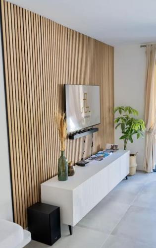 un salon avec une télévision sur un mur dans l'établissement Havre de Paix avec jardin - Cote Azur Ste Maxime, à Sainte-Maxime
