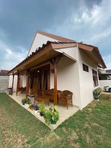 a small white house with a porch and some plants at Belgareti Modern Ethnic House Cipanas Puncak in Cibadak