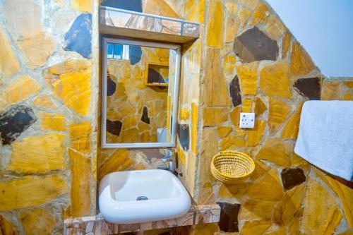 a stone bathroom with a sink and a window at Unique Homestay in Karatu