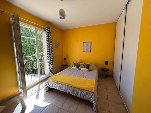 une chambre avec un lit aux murs jaunes et une fenêtre dans l'établissement La Villa Nawengo, au Thor