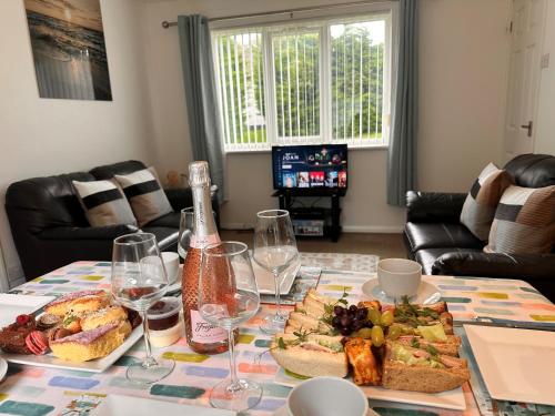 a table with a bottle of wine and a plate of food at SeaBreeze Lodge, located between Penzance & St Ives - A sanctuary to relax & unwind with activities on the doorstep for all the family in Penzance
