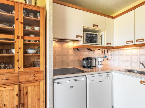 une cuisine avec des appareils électroménagers blancs et des armoires en bois dans l'établissement Apartment Les Marines-16 by Interhome, à La Foux
